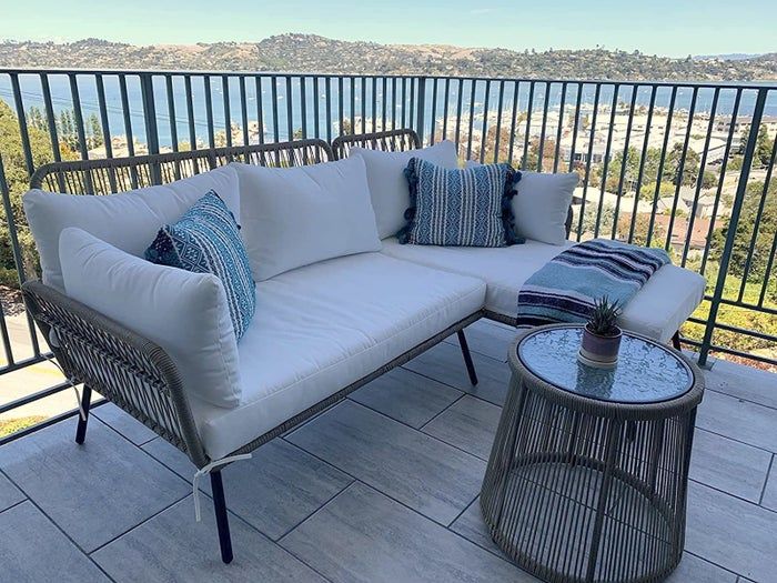 A sofa chaise sectional paired with a small table, set on a balcony