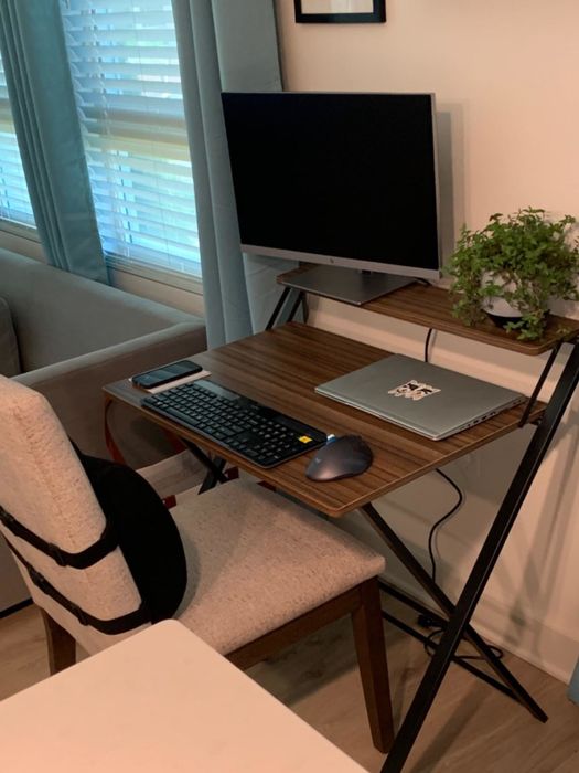 The woodgrain and black desk with a lower level for a keyboard, laptop, or mouse, and a smaller upper level for displaying items or placing monitors.