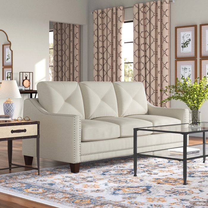 A taupe sofa with metal tufting, perfectly placed in a cozy living room that invites relaxation and style.