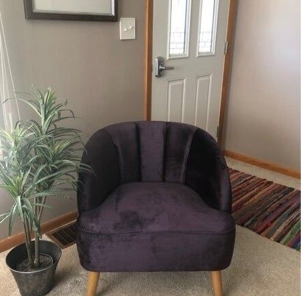 A luxurious accent chair with textured fabric is positioned beside a potted plant in a warm, carpeted space