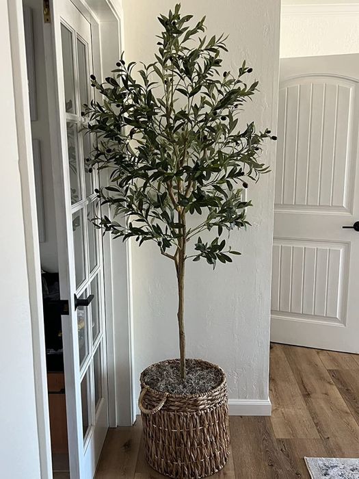 The reviewer's faux olive tree is placed in a living room.