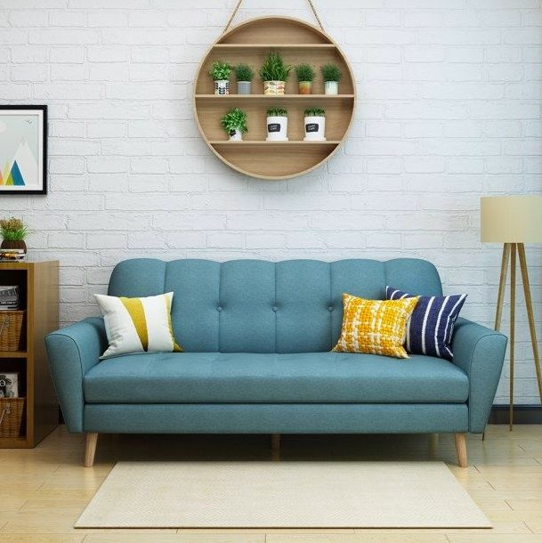 A blue sofa complemented by throw pillows and a nearby floor lamp creates a cozy and inviting atmosphere.