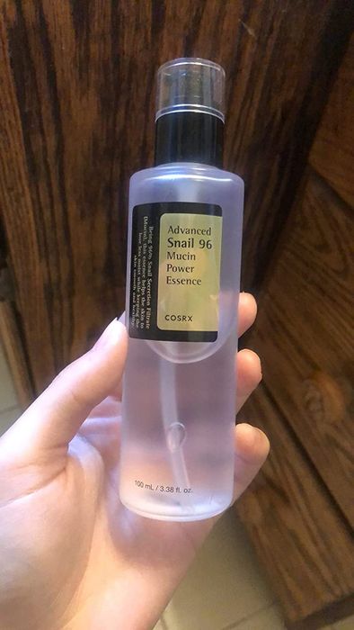 A reviewer holding the bottle of Snail Mucin Essence.