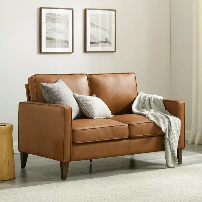 A brown loveseat adorned with throw pillows and a blanket, adding warmth and comfort to any space.