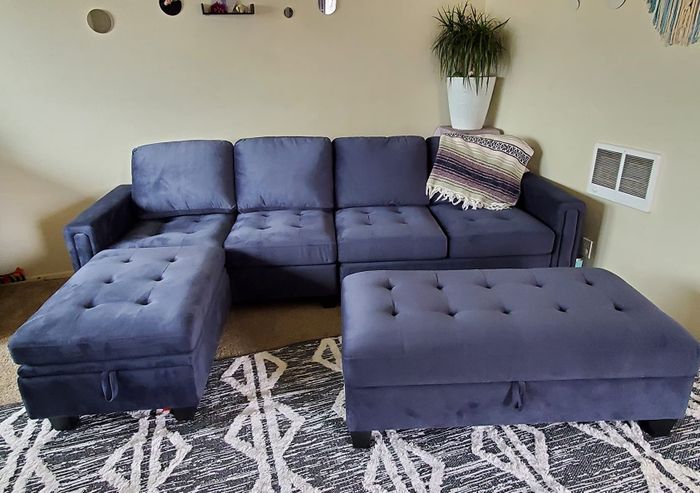 A reviewer’s photo of the navy blue couch paired with an ottoman.
