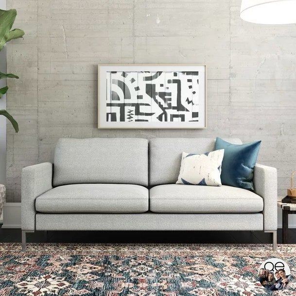 A gray sofa paired with two throw pillows and a beautiful piece of artwork hung above it.