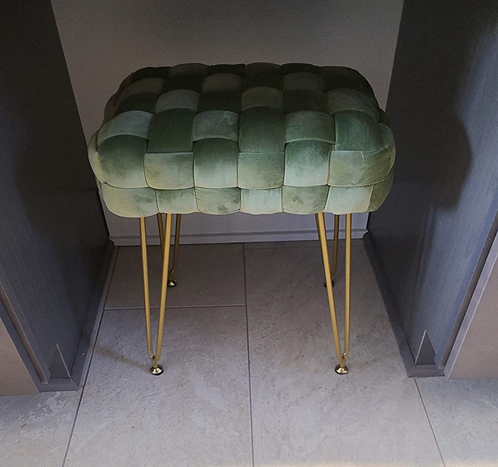 A reviewer’s image of a green product with gold curved legs placed beneath a gray table.