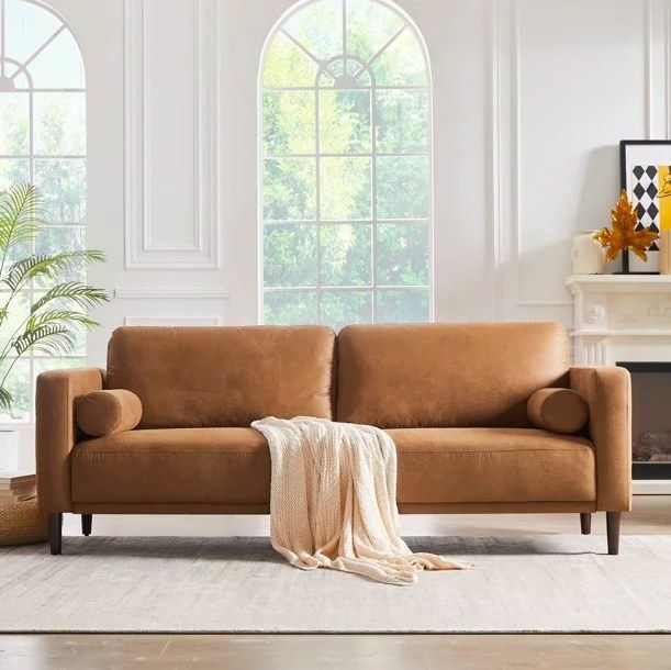 A brown sofa with a cream throw draped over it, nestled in a bright white living room.