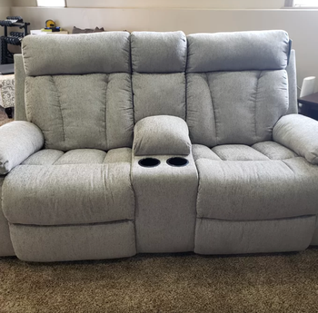 A reviewer's photo showcasing a gray reclining sofa.