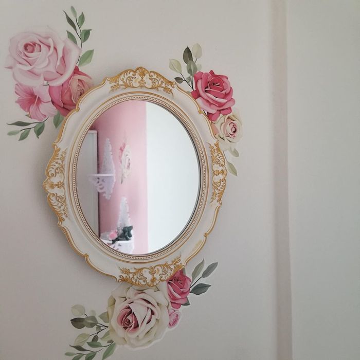 A reviewer's mirror hangs on a wall with a beautiful floral rose pattern as the backdrop.