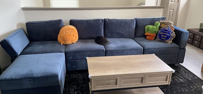 A reviewer’s photo showcasing a blue L-shaped couch adorned with stuffed animals.