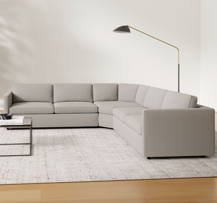 A chic lifestyle image of a gray L-shaped couch placed in a modern living room setting.