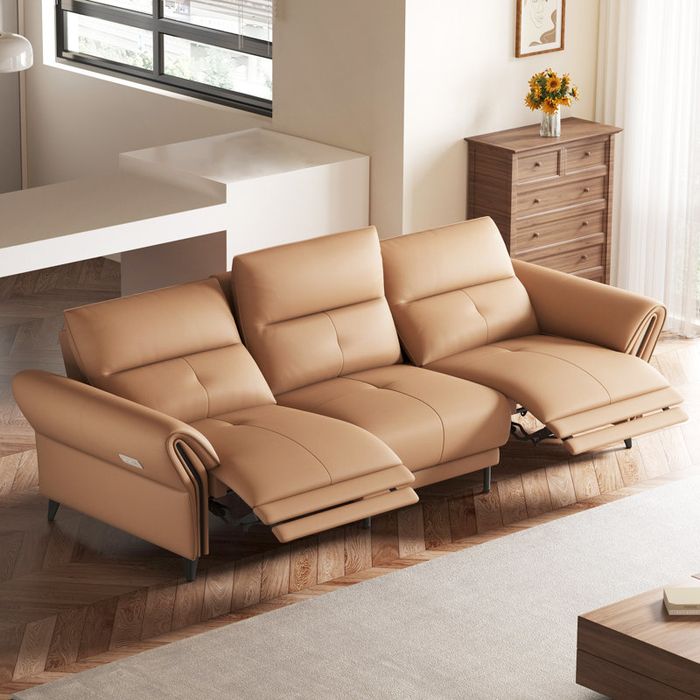 A modern beige recliner sofa in an elegant living room, featuring a window and a stylish wooden dresser.