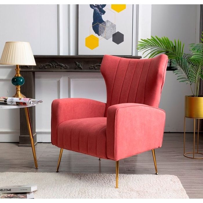 A contemporary chair with gold legs, placed beside a table and lamp in an elegant living room