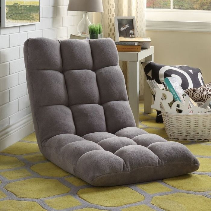 A tufted floor chair offering comfort, situated in a cozy room next to a basket filled with magazines