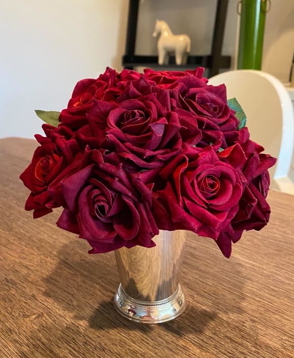 A reviewer's bouquet of faux red roses beautifully arranged in a silver vase, adding charm to the room.