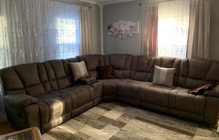 An image from a reviewer showcasing the comfort of a gray microfiber reclining couch.