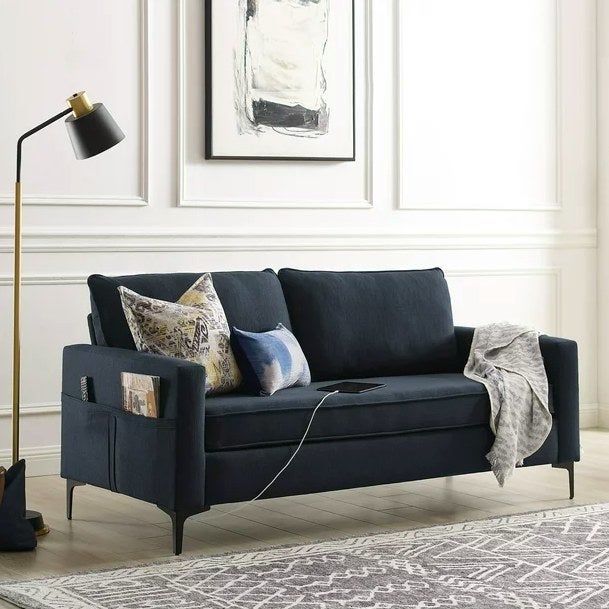 A navy blue sofa adorned with throw pillows and a blanket, placed next to a patterned rug for added style.