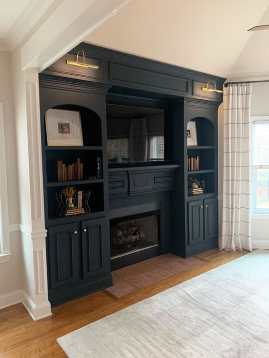 A reviewer has placed two gold library lights over built-in bookshelves.