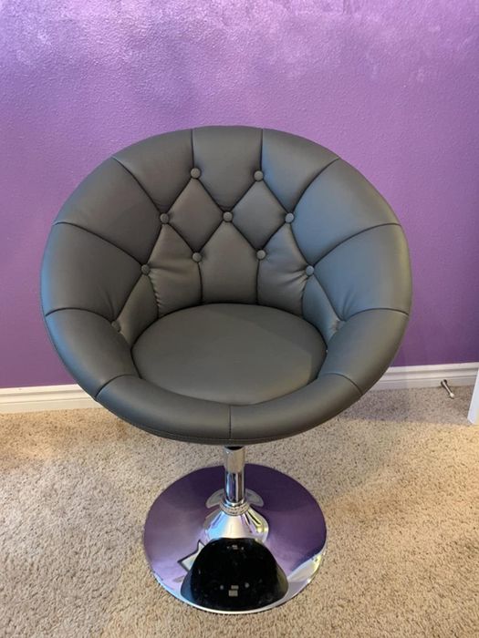 Reviewer image showing a round saucer-style black faux leather chair with a tufted seat and silver circular base, placed on a carpet.