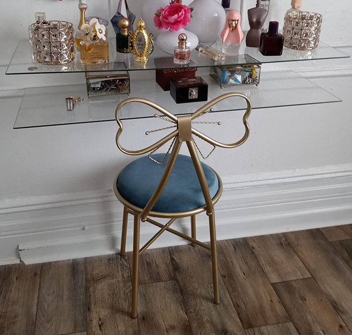 Reviewer image featuring a blue velvet seat beneath acrylic floating shelves, with perfume and makeup arranged on top.