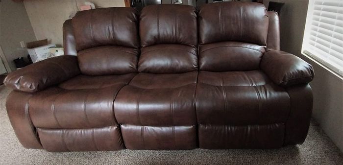 A reviewer’s photo of a brown leather three-seater sofa.