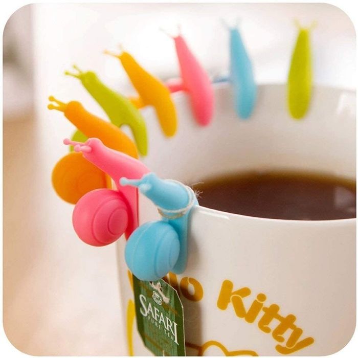 Eight snails in green, orange, blue, and pink resting on the edge of a mug.