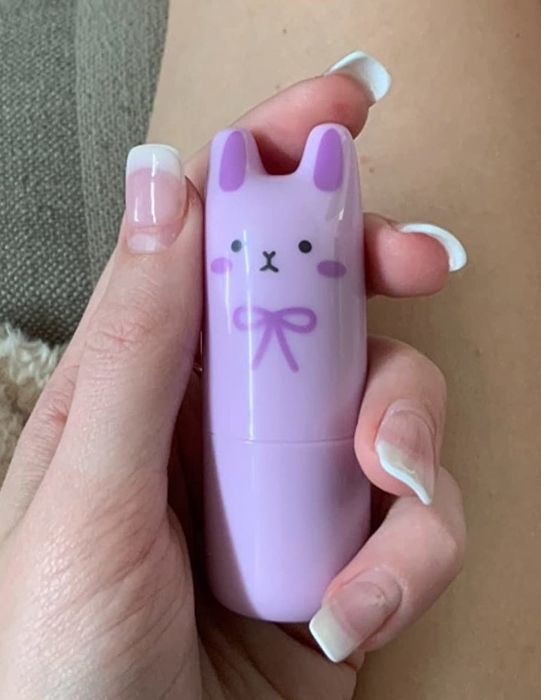 A reviewer holding a purple bunny-shaped perfume stick.