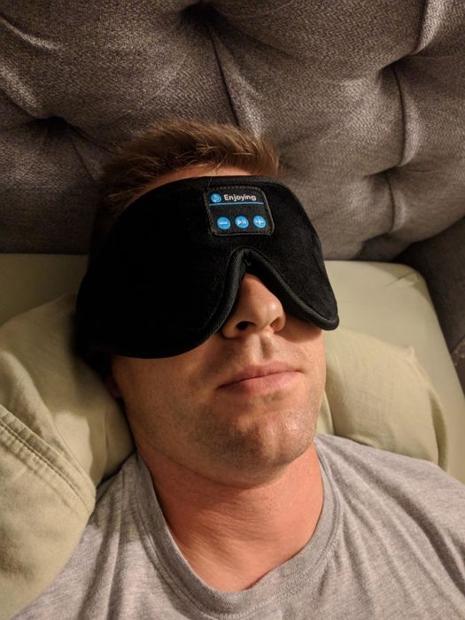 A reviewer wearing the Bluetooth-enabled sleep mask for a peaceful rest.