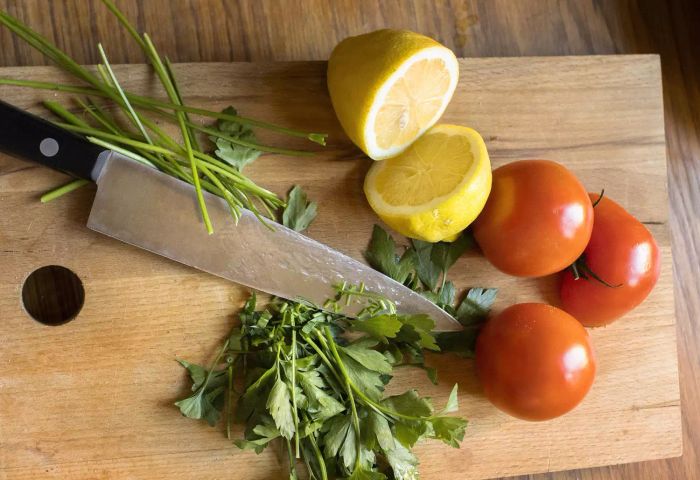 Tomatoes, lemons, and herbs placed on a cutting board