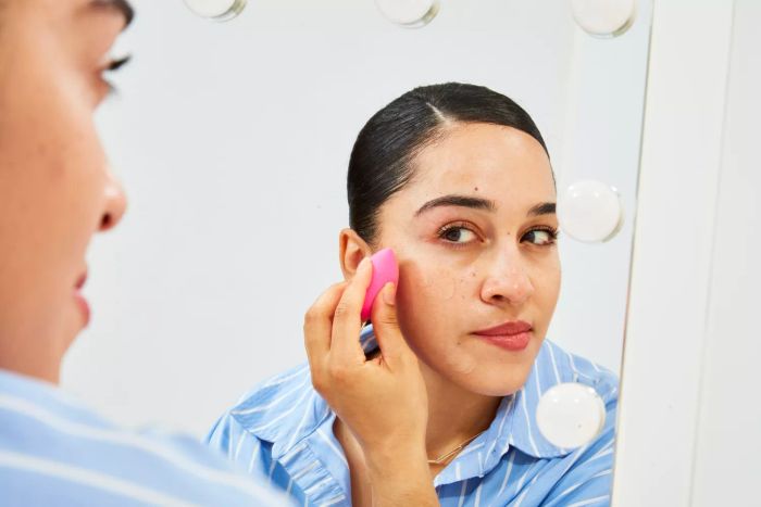 A person applying foundation in front of a mirror