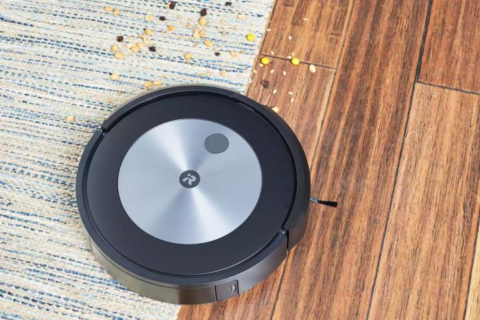 iRobot Roomba J7+ Self-Emptying Robot Vacuum cleaning up trail mix from wood floors and a rug