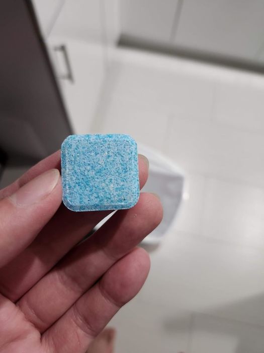 A hand holding a laundry machine cleaning pod.