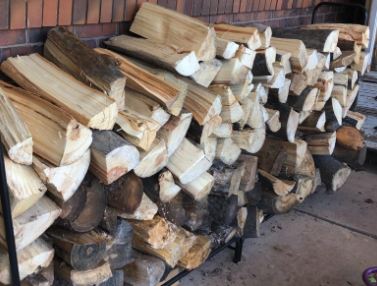 A reviewer's photo featuring neatly stacked firewood logs
