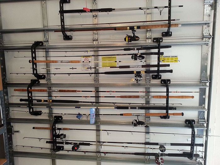 A collection of fishing rods neatly arranged along a garage wall