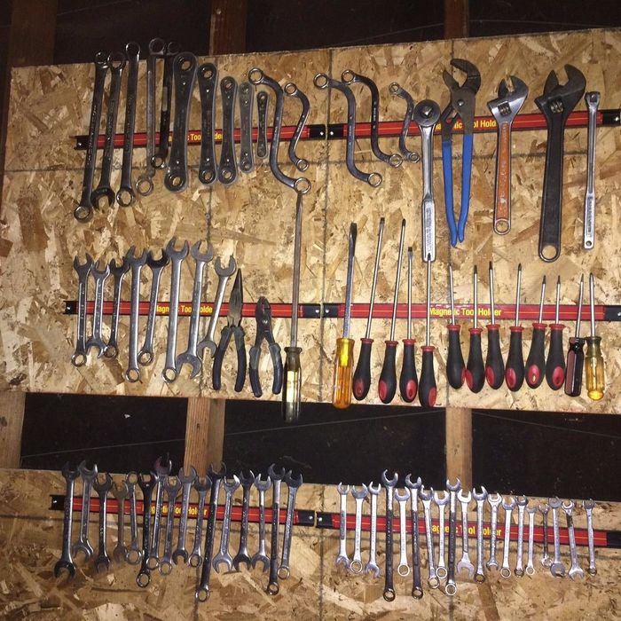 Variety of wrenches and screwdrivers neatly arranged on a wooden pegboard