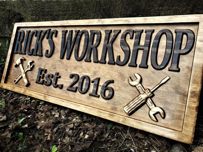 A wooden sign reading 'Rick's Workshop Est. 2016', with images of tools displayed on each side