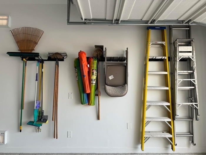 Wall-mounted storage system designed to hold various garden tools and ladders