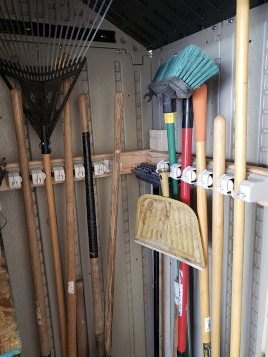 A reviewer’s photo showing two broom organizers mounted along the garage walls