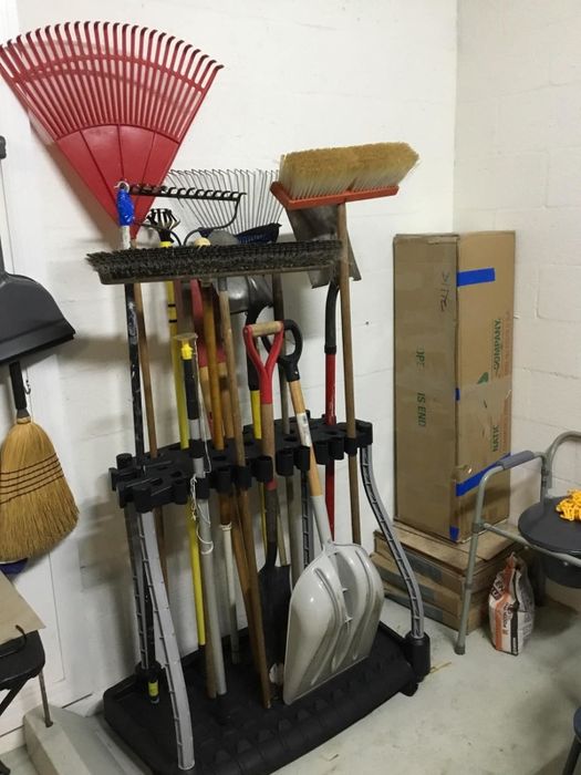A collection of cleaning tools neatly arranged in a corner storage unit within a garage