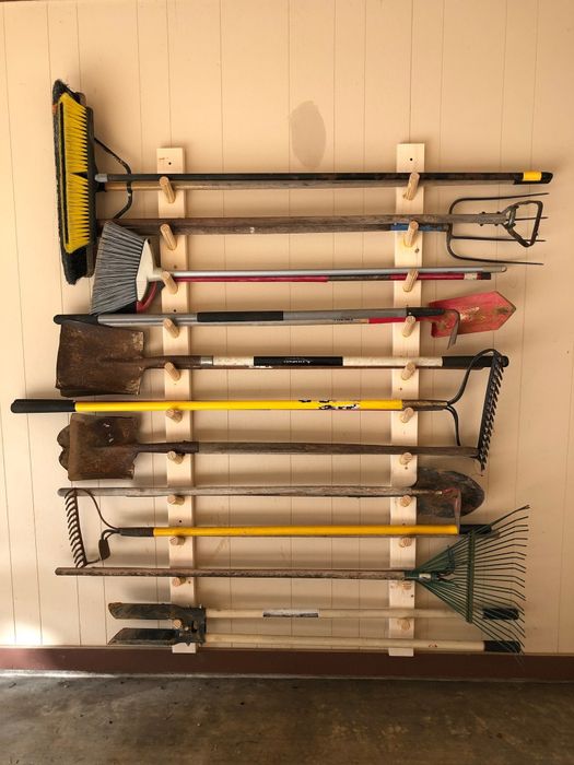 Various garden tools, including shovels and rakes, hung neatly on a garage wall