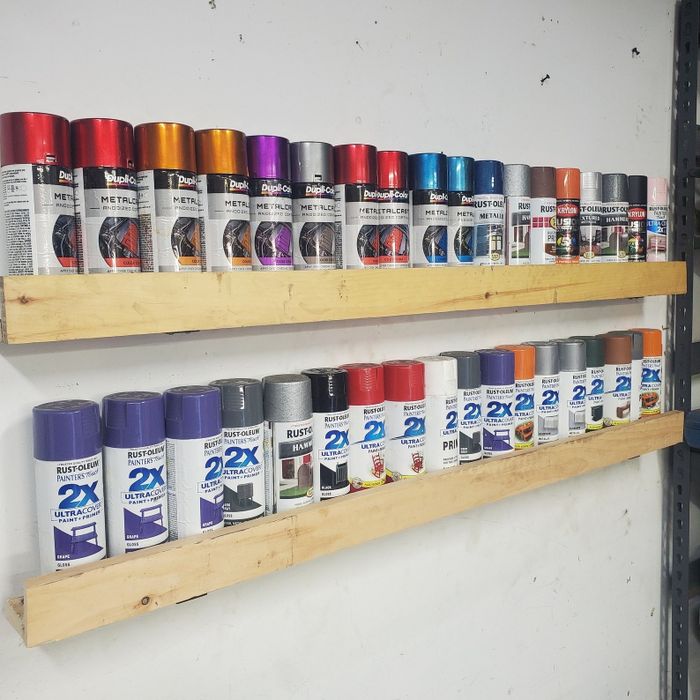 Shelves showcasing a variety of spray paint cans in different finishes and brands.