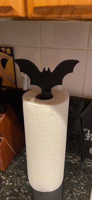 The bat-shaped paper towel holder with a roll of paper towels resting on a reviewer's countertop