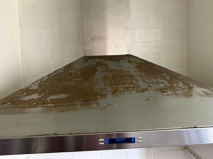 A metal kitchen range hood covered in grease stains