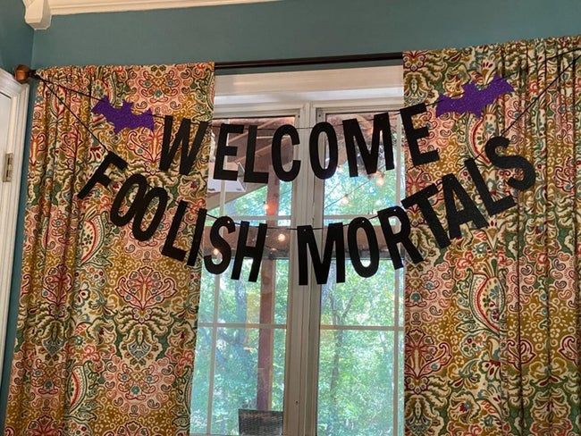 A sign reading 'WELCOME FOOLISH MORTALS' is hung in a reviewer's window.