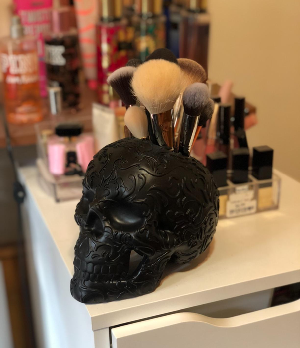 A black skull filled with makeup brushes on a reviewer’s vanity