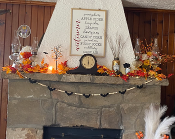 A reviewer’s mantel adorned with colorful autumn leaves, with the garland hanging below