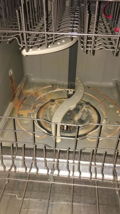 A dishwasher with brown stains on the bottom before cleaning