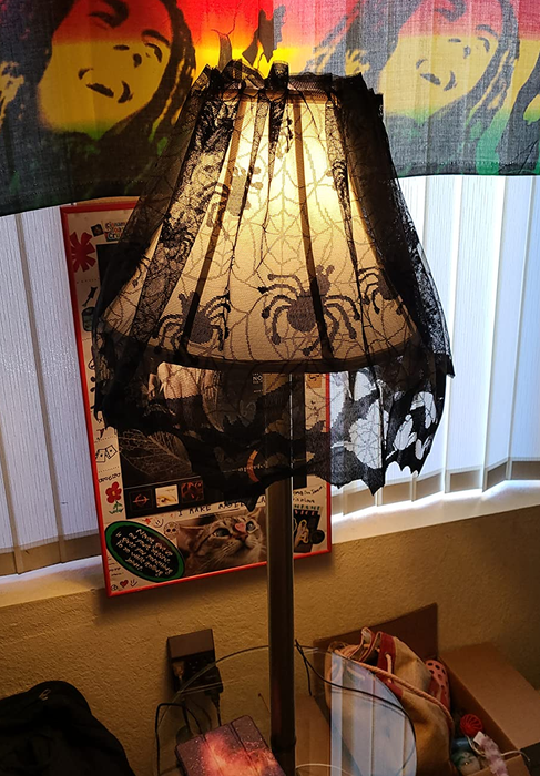 A spider web lampshade cover is wrapped around a reviewer's cone-shaped lamp.