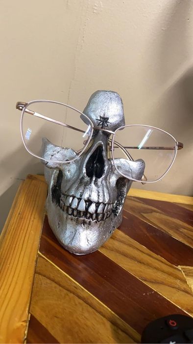 A silver skull with a pair of glasses placed on it